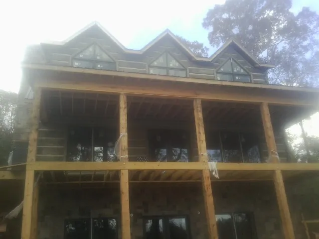 Dormers and porch framing on a large log home under construction — Roof Coating work by our crew in Orwell