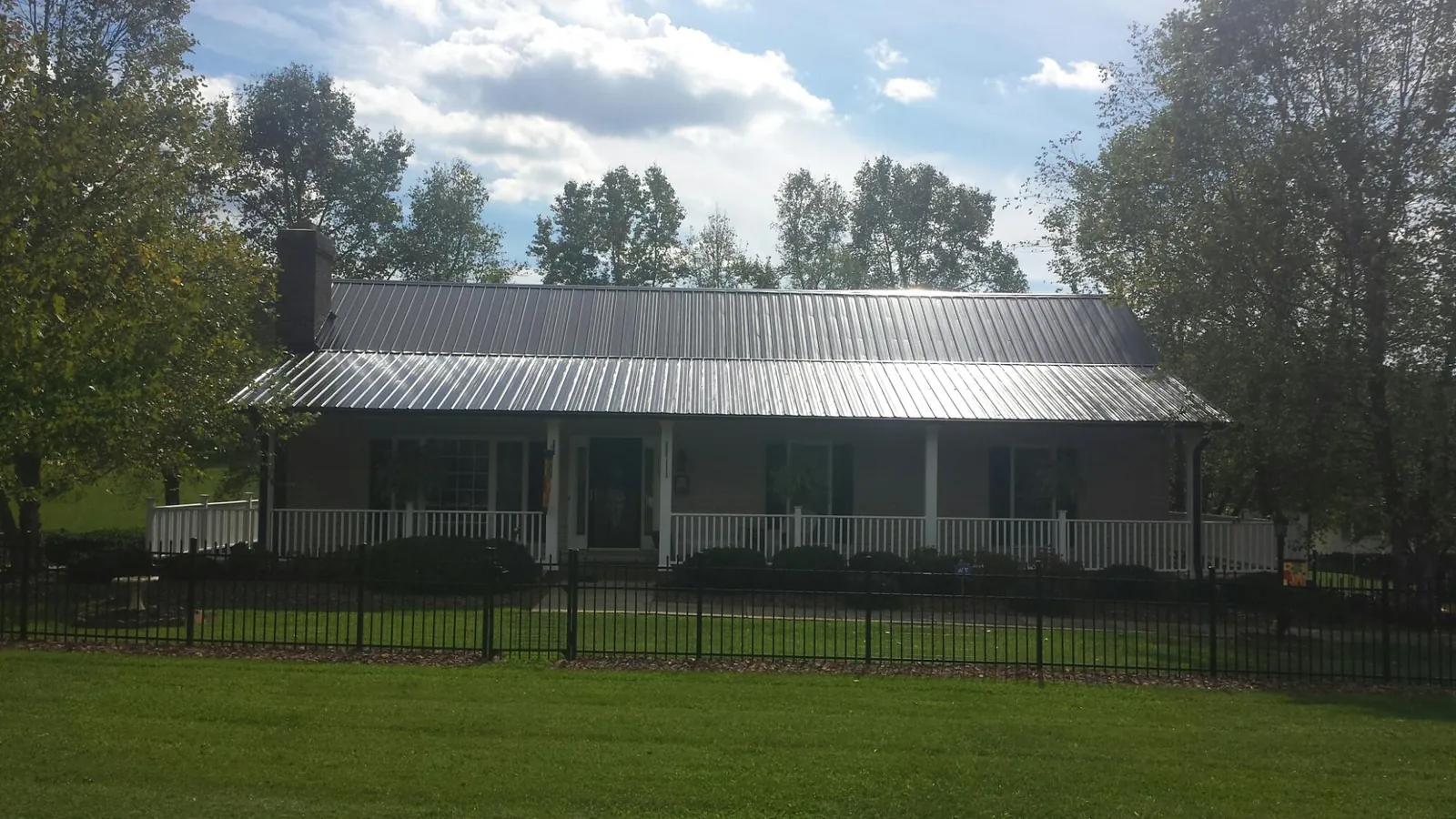 Gray metal roof on a brick ranch with a full width front porch — Gutter Guard Installation work by our crew in Orwell