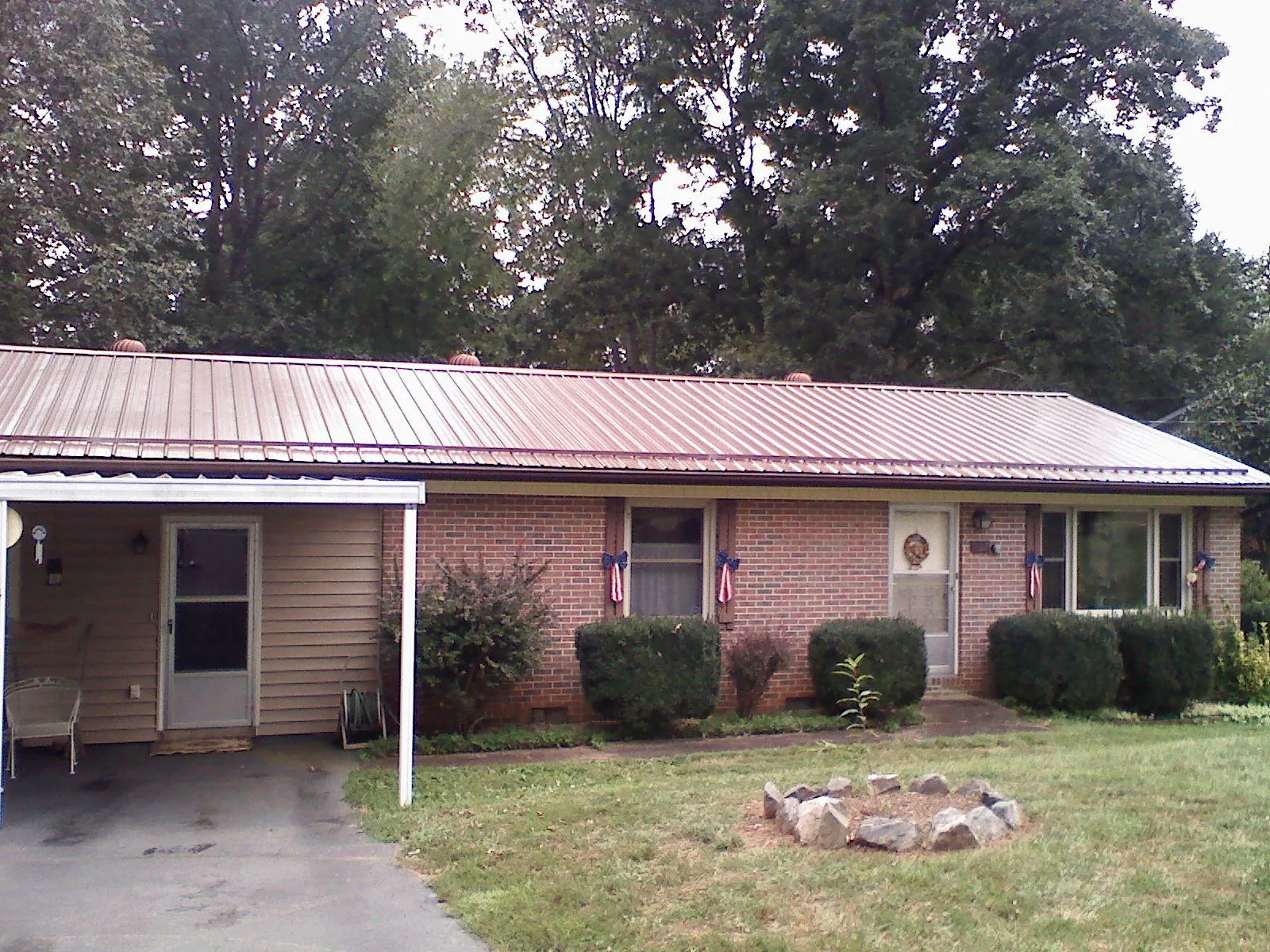 Bronze metal roof and carport on a brick ranch home — Roof Repair work by our crew in Orwell