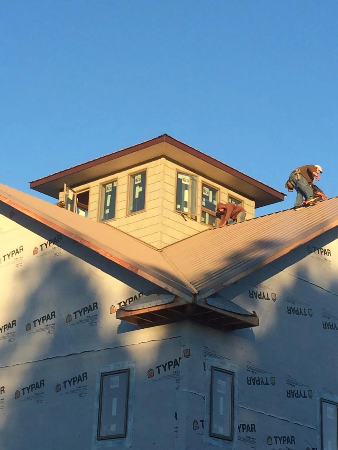 Roofers working around a rooftop cupola on a new metal roof at sunset — Roof Waterproofing in Orwell by Roofing Brothers